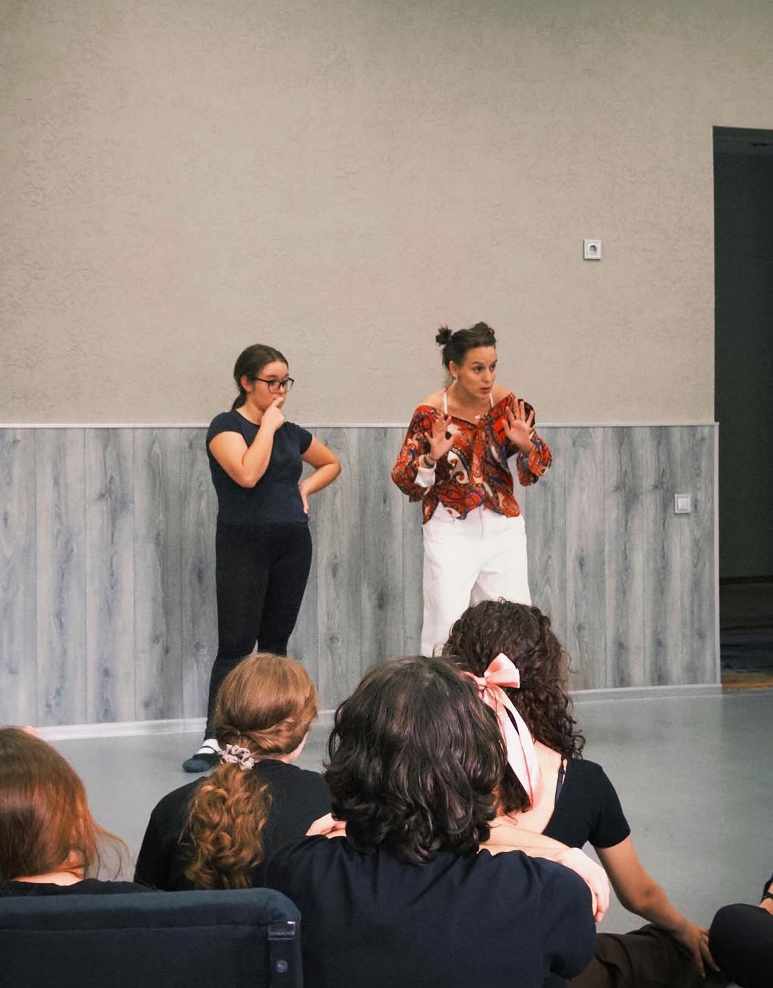 An acting instructor is standing with a student in the classroom